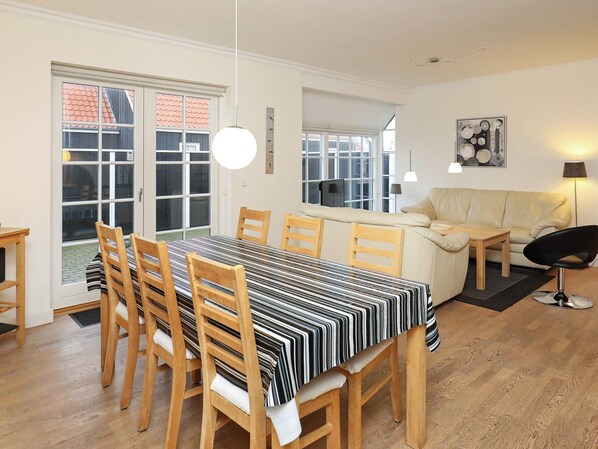 A dining area with a striped tablecloth, wooden chairs, and a sofa.