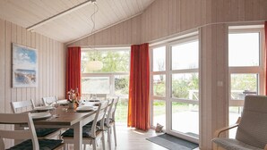 A dining area with a wooden table set for four, white chairs, and a bench.