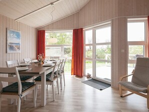 Un coin repas avec une table en bois dressée pour quatre personnes, des chaises blanches et un banc.