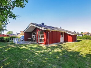 A red single-story building with a covered porch and a small attached garage. - Holiday Home in GrÃ¶mmitz (Groemitz)