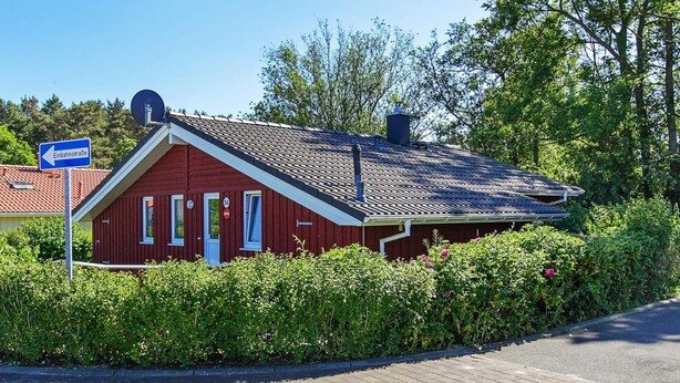 A red building with a sloped roof, a chimney, and a sign indicating a left turn.