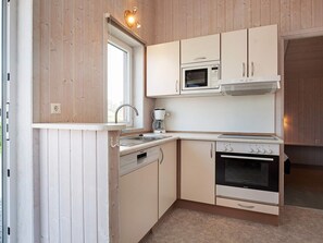 A compact kitchen with a microwave, stove, and sink. - Holiday Home in GrÃ¶mmitz (Groemitz)