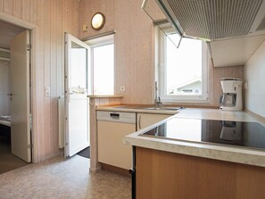 A kitchen with wooden walls, a dishwasher, a coffee maker, and a window providing natural light. - Holiday Home in GrÃ¶mmitz (Groemitz)