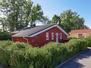 A red wooden house with a sloped roof, a chimney, and a small porch. - Holiday Home in GrÃ¶mmitz (Groemitz)