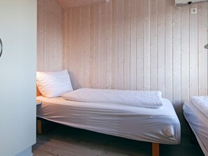A single bed with a wooden headboard in a room with a sloped ceiling. - Holiday Home in GrÃ¶mmitz (Groemitz)