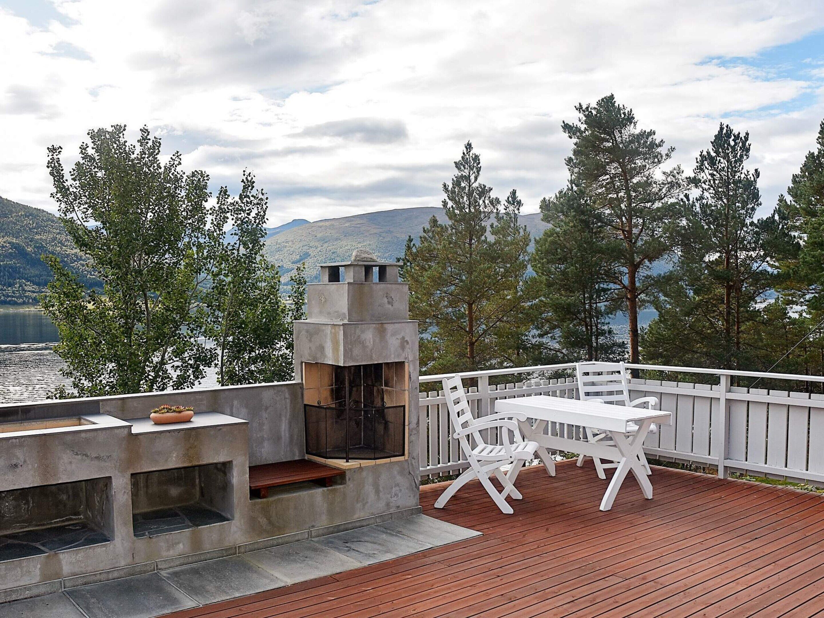 Une terrasse dotée d’un barbecue et d’un espace salon offrant une vue sur un lac et des montagnes.