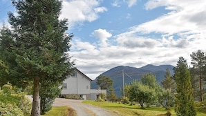 Eine ländliche Straße führt zu einem zweistöckigen Haus mit Bergblick.