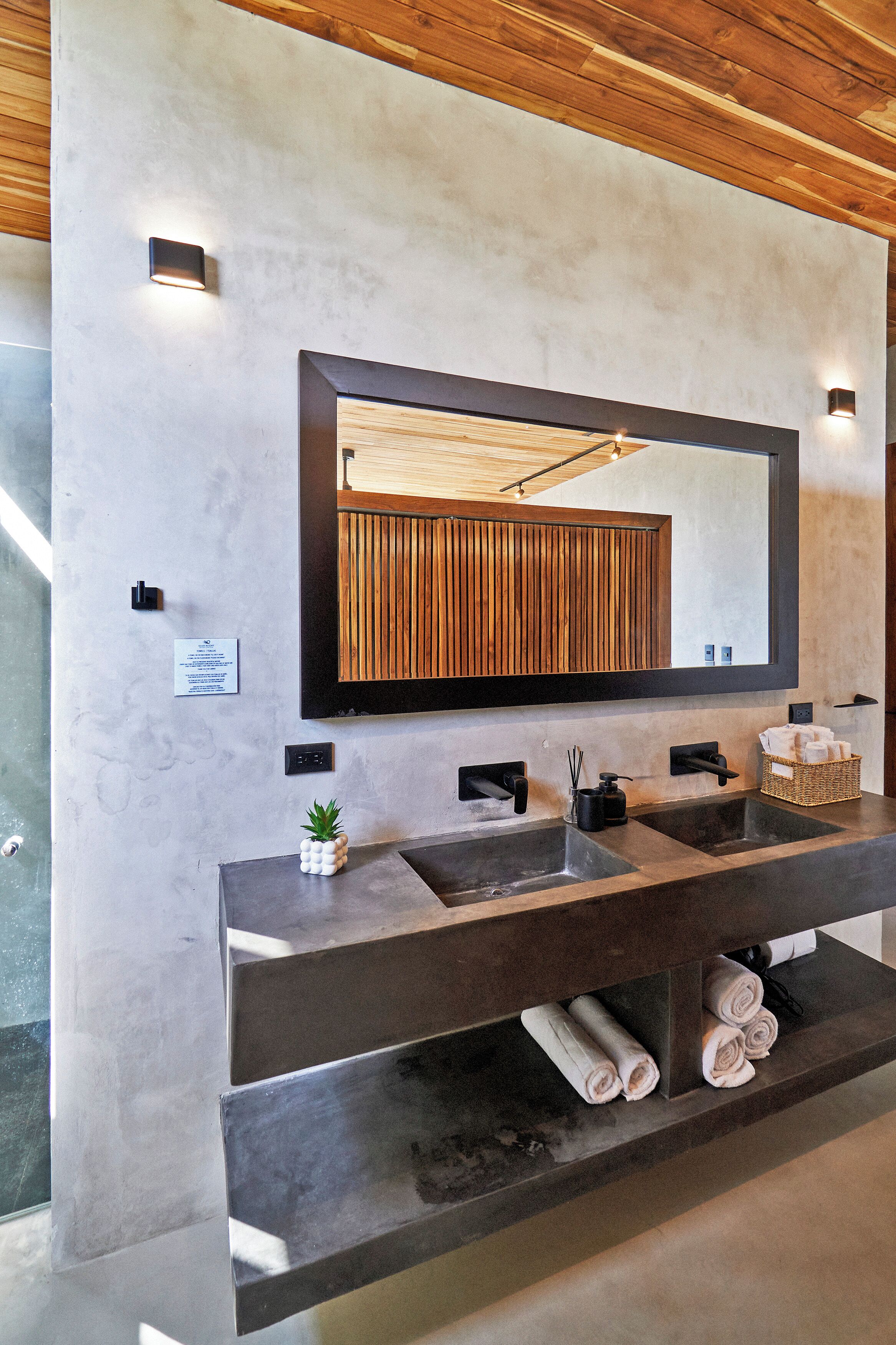 A modern bathroom with a large mirror, two sinks, and a wooden panel wall.