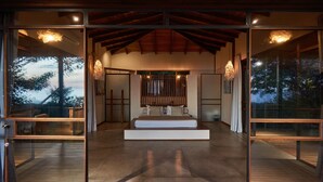 Ein modernes Schlafzimmer mit einem großen Bett, Glastüren und Blick ins Freie.