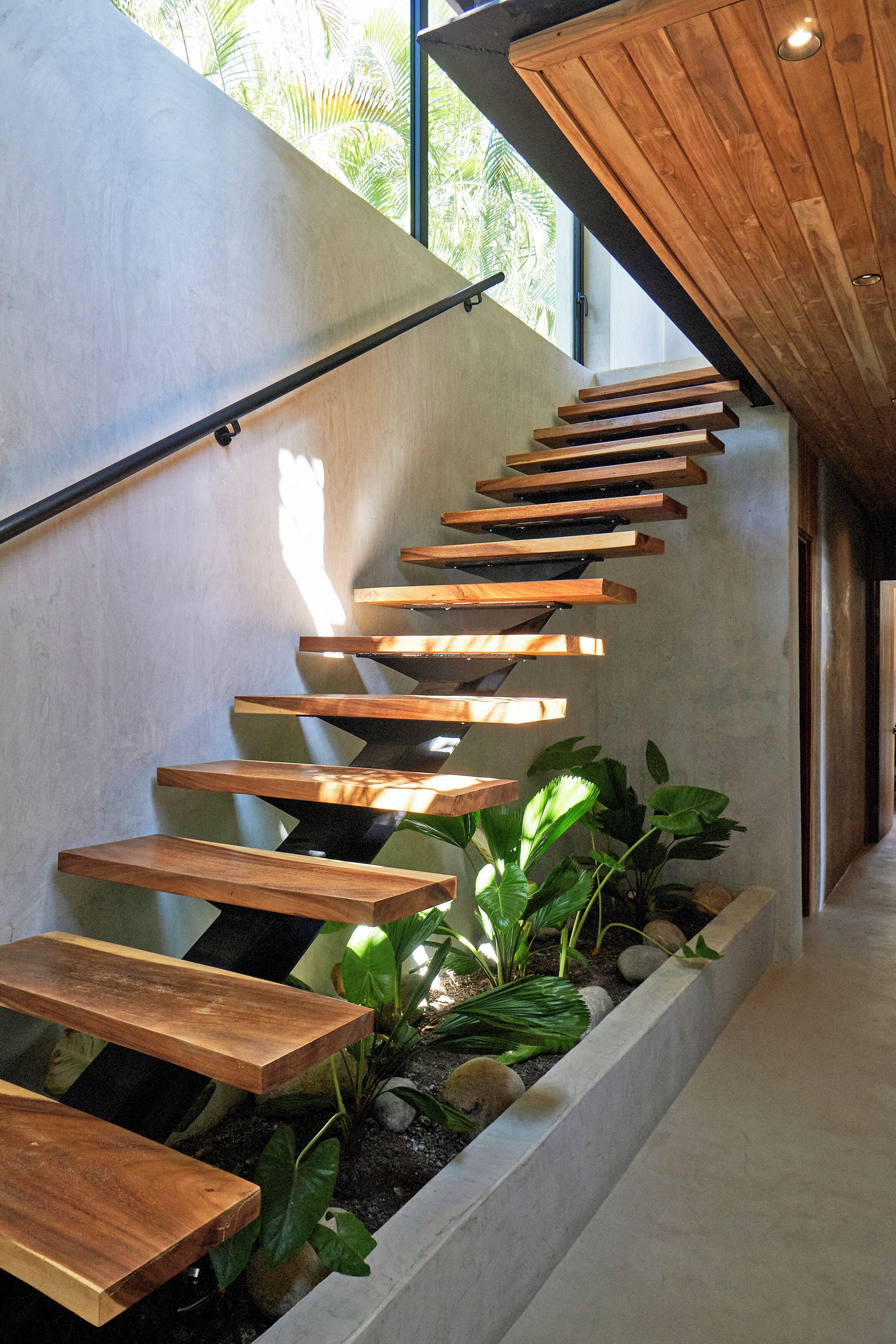 A modern staircase with wooden steps and a concrete wall.