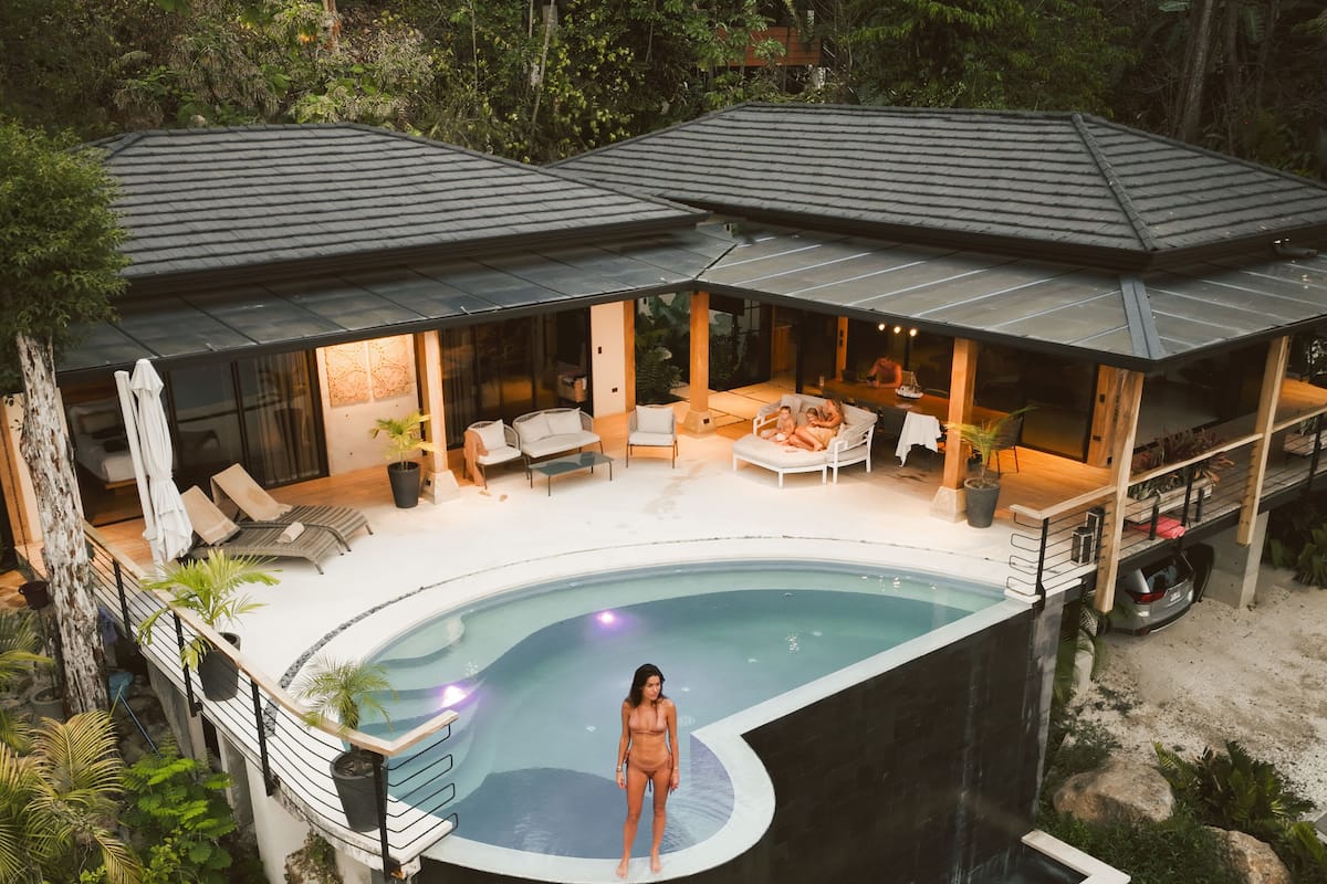 Uma casa moderna com piscina, área de estar externa e vegetação exuberante.
