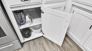 A kitchen with white cabinets, a blender, a coffee maker, and a basket.