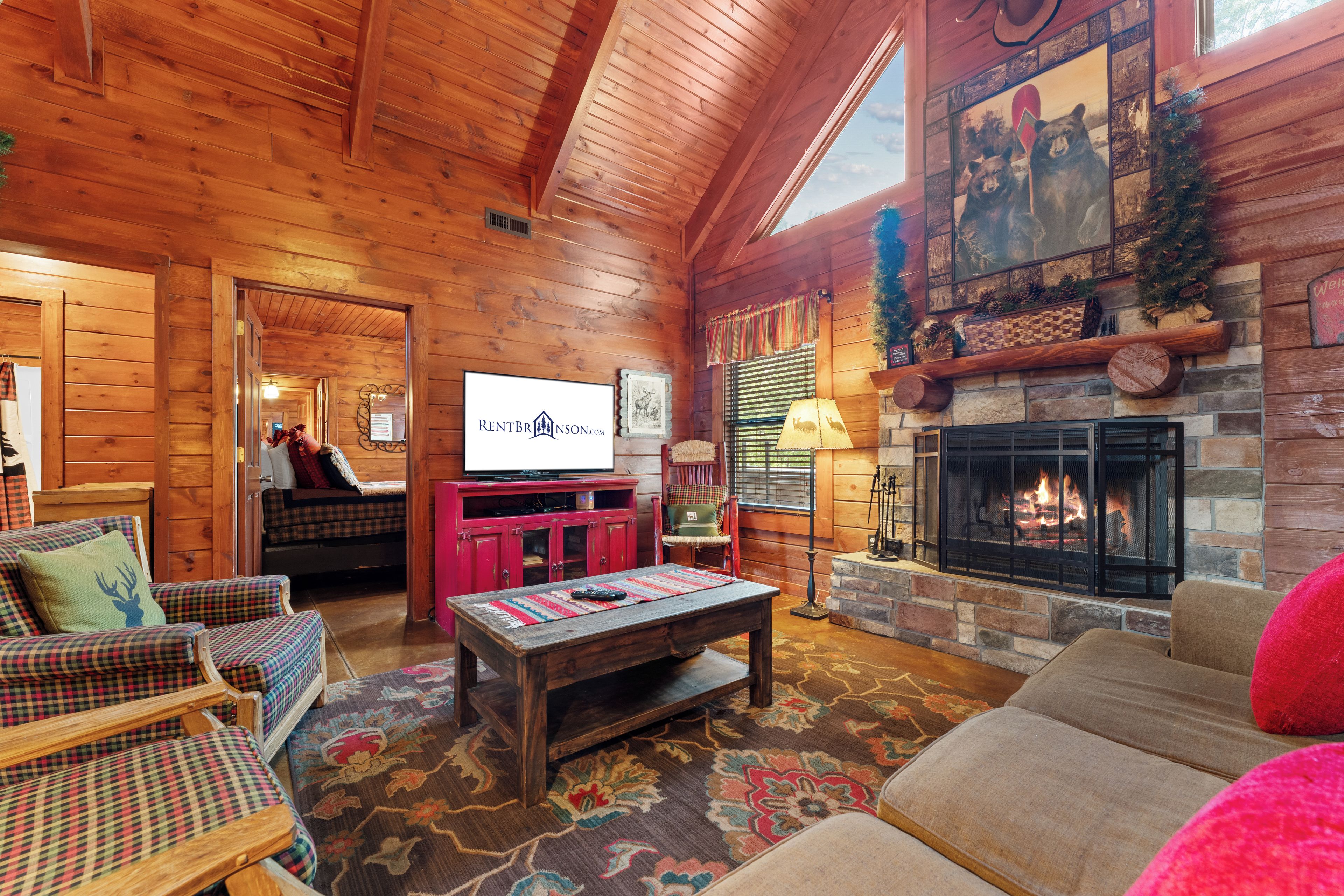A cozy log cabin interior with a fireplace, a television, and a comfortable seating area.