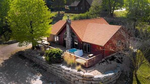A log cabin with a stone foundation, a wooden deck, and a swimming pool.