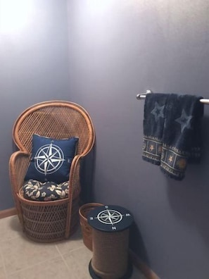 A cozy corner with a wicker chair and a small trash bin, both featuring a compass design.