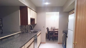 A compact kitchen with a granite countertop, a sink, and a dining area with a table and chairs. - Windjammer 33 (Osage Beach)