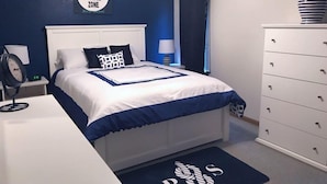 A bedroom with a bed, a dresser, a nightstand, a lamp, a clock, and a 'No Wake Zone' sign on the wall. - Windjammer 33 (Osage Beach)