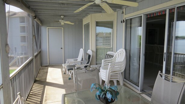A covered outdoor area with white plastic chairs, a glass table, and ceiling fans. - Regatta BAY 404 (Lake Ozark)