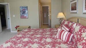 A bedroom with a floral bedspread, a nightstand with a lamp, and a framed picture on the wall. - Regatta BAY 404 (Lake Ozark)