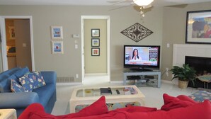 A living room with a television, a ceiling fan, and a fireplace. - Regatta BAY 404 (Lake Ozark)