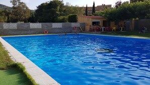 Ein rechteckiger Swimmingpool mit glatter, blauer Wasseroberfläche, umgeben von einer Steinmauer mit weißen Gitterelementen.