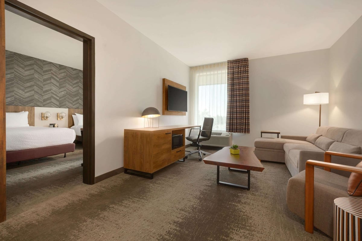 A hotel room with a bed, a desk, a sofa, and a TV.