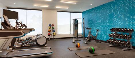 Une salle de sport moderne équipée de tapis de course, de vélos d’appartement et de divers appareils d’exercice.