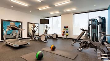 A modern gym with various exercise equipment, including treadmills, elliptical machines, and free weights.