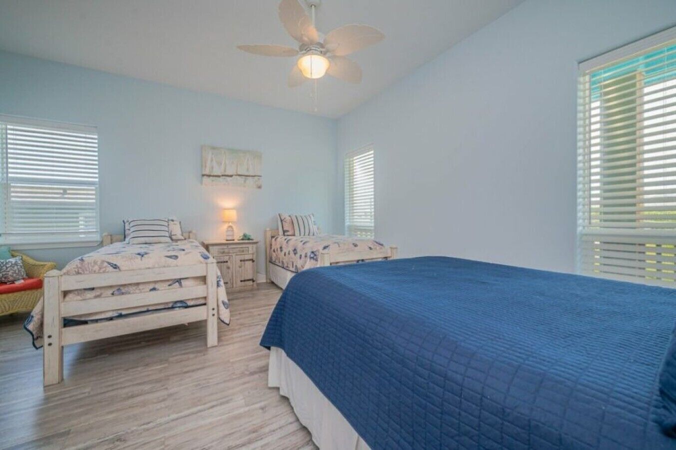 A bedroom with two beds, a ceiling fan, and a window with blinds.