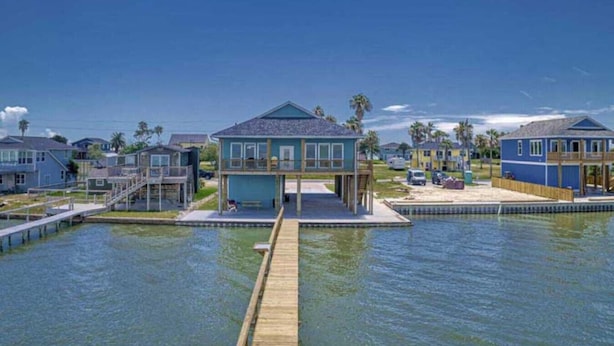Una propiedad frente al agua con un muelle que lleva a una casa con balcón.