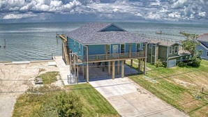 Una casa frente al mar de dos pisos, con balcón, terraza cubierta y vista al océano.