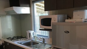 Una cocina compacta con estufa a gas, un fregadero, microondas y refrigerador.