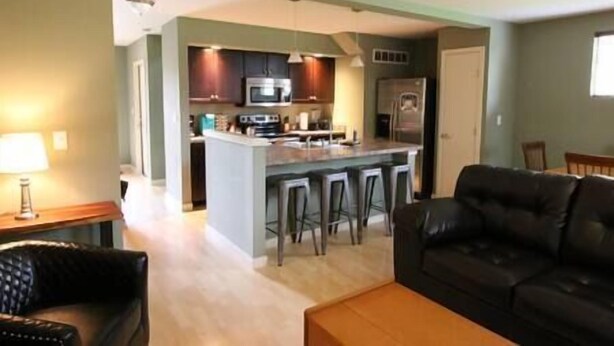 A modern kitchen with a central island, bar stools, and a dining area with a black leather couch. - Athens townhouse, 4 beds, 2 kings. 2 twins, in 2 bedrooms, 2,5 baths, FREE WIFI, (Athens)
