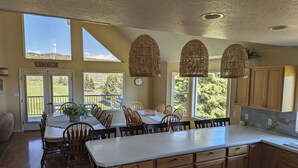 A spacious kitchen with a large island, wooden cabinets, and a dining area with a view of the outdoors.