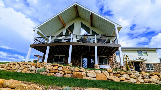 A two-story house with a stone foundation, a covered porch, and a balcony.