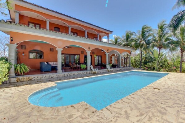 A two-story building with a swimming pool and outdoor seating area. - Oceanview Villa w/ private pool, beachside access in Rancho Santana!  (El Limón)