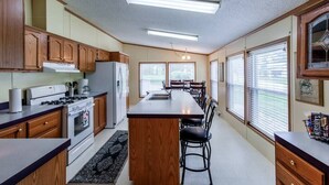 Une cuisine avec des meubles de rangement en bois, un îlot central, une cuisinière et un réfrigérateur.