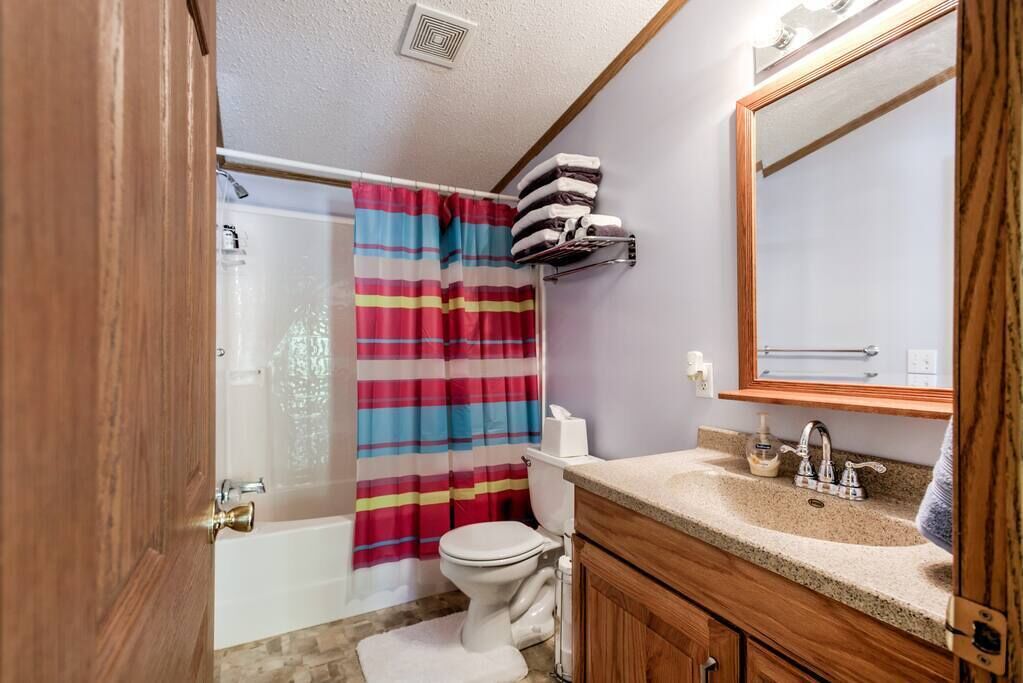 A bathroom with a bathtub, toilet, and vanity with a mirror.