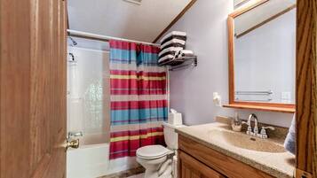 A bathroom with a bathtub, toilet, and vanity with a mirror.