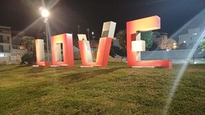 Illuminated letters spelling "LOVE" on a grassy field at night.