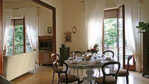 A dining room with a round table set for four, surrounded by chairs. There is a wooden cabinet with drawers and a mirror on the wall. - Residenza Oltrarno, an elegant apartment in the historic center of Florence (Firenze)