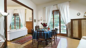 A dining area with a table set for four, a sofa, a cabinet, and a large mirror. - Residenza Oltrarno, an elegant apartment in the historic center of Florence (Firenze)