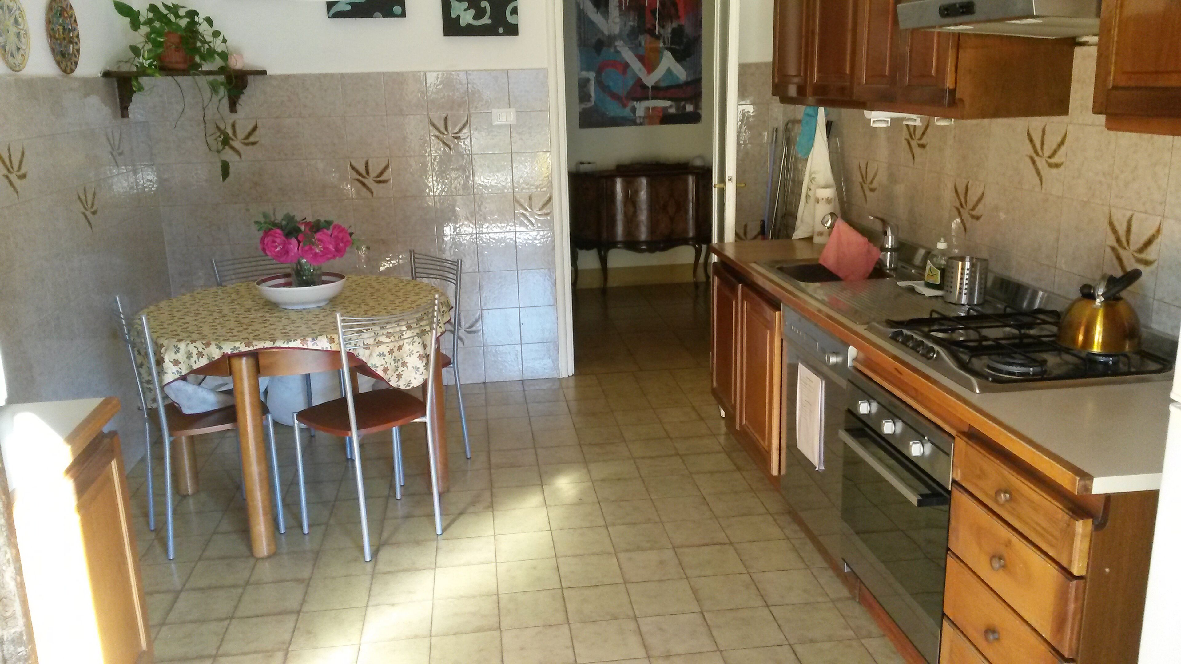 A kitchen with a dining table, chairs, a stove, and a sink.