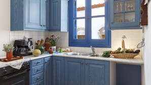 Una cocina con armarios azules, una cafetera, un lavamanos y diversos utensilios de cocina.
