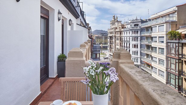 A balcony with a table set for breakfast, including croissants and coffee, overlooking a cityscape with historic buildings. - Mirakruz Terrace by FeelFree Rentals (San Sebastin)