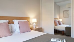 A hotel room with a bed, bedside lamps, a nightstand, and a mirror reflecting the room. - Mirakruz Terrace by FeelFree Rentals (San Sebastin)