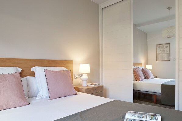 A hotel room with a bed, bedside lamps, a nightstand, and a mirror reflecting the room. - Mirakruz Terrace by FeelFree Rentals (San Sebastin)