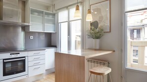 A modern kitchen with white cabinets, a Bosch oven, and a wooden island with a stool. - Mirakruz Terrace by FeelFree Rentals (San Sebastin)