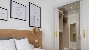 A bedroom with a wooden headboard, a bed with white and gray bedding, and three framed artworks on the wall. - Moneo by FeelFree Rentals (San Sebastián)