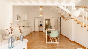A modern kitchen with white cabinets, a dining table with chairs, and a staircase with wooden steps. -  DOMUS DE SILVA - Apartment in the historic center of Cagliari (Cagliari)
